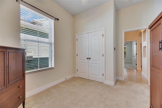 unfurnished bedroom featuring a closet, light colored carpet, and baseboards