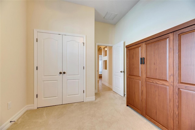 unfurnished bedroom with visible vents, light colored carpet, a closet, and baseboards