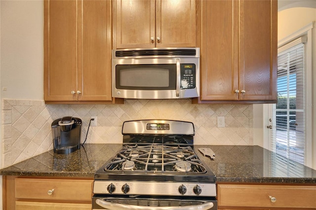 kitchen featuring backsplash, stainless steel appliances, and dark stone countertops