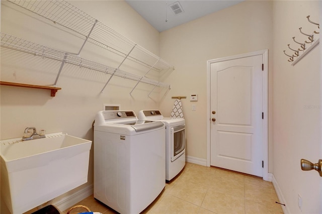 washroom with washing machine and clothes dryer, visible vents, light tile patterned floors, laundry area, and a sink