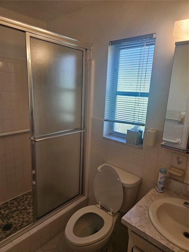 bathroom with vanity, toilet, an enclosed shower, and tile walls