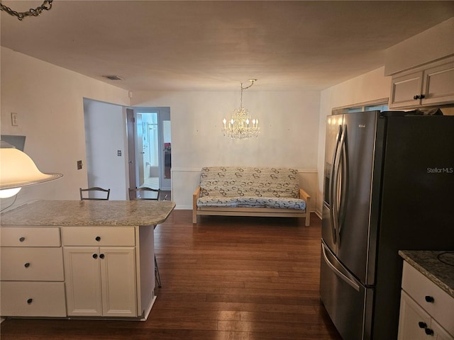 kitchen featuring dark hardwood / wood-style floors, a notable chandelier, stainless steel fridge, decorative light fixtures, and white cabinets