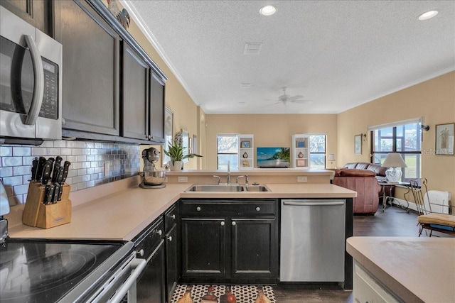 kitchen featuring ceiling fan, sink, backsplash, a textured ceiling, and appliances with stainless steel finishes