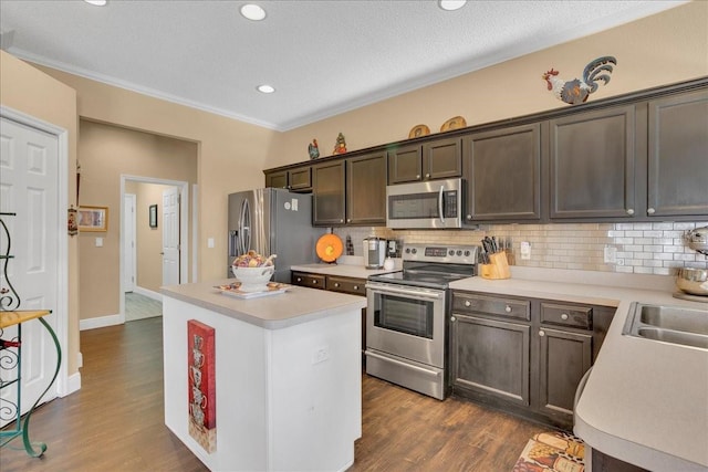 kitchen with a center island, dark wood-type flooring, stainless steel appliances, tasteful backsplash, and dark brown cabinets