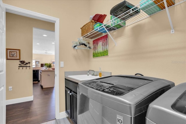 laundry area with cabinets, wood-type flooring, washing machine and dryer, and sink