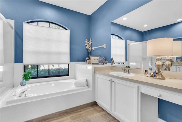 bathroom featuring vanity and tiled tub