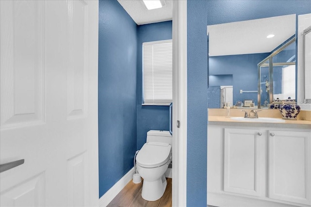 bathroom with walk in shower, vanity, a textured ceiling, wood-type flooring, and toilet