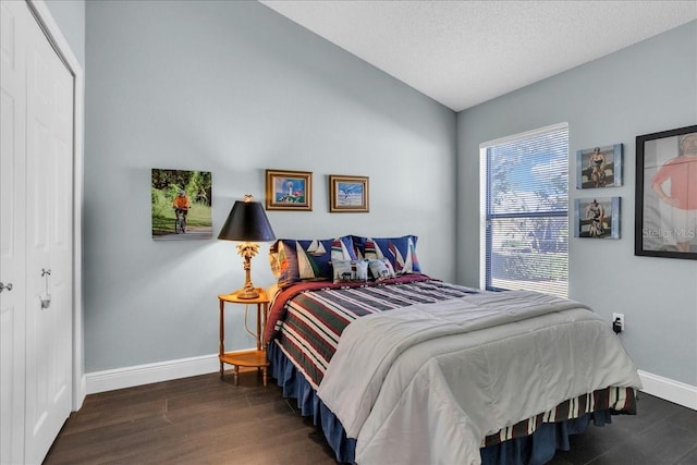 bedroom featuring a textured ceiling, a closet, dark wood-type flooring, and vaulted ceiling