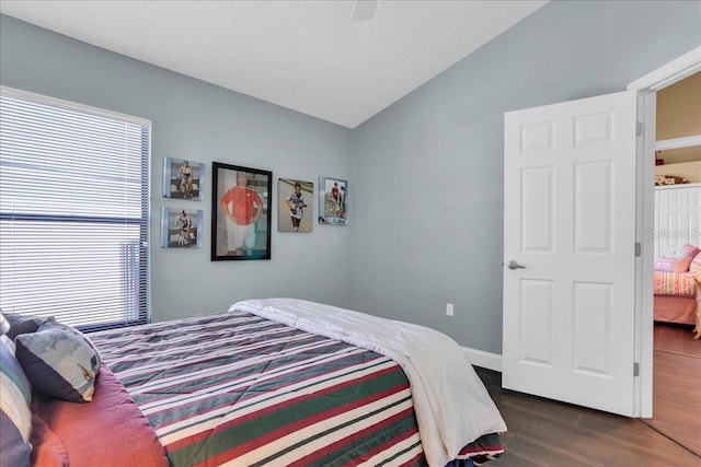 bedroom with vaulted ceiling, multiple windows, ceiling fan, and dark hardwood / wood-style floors