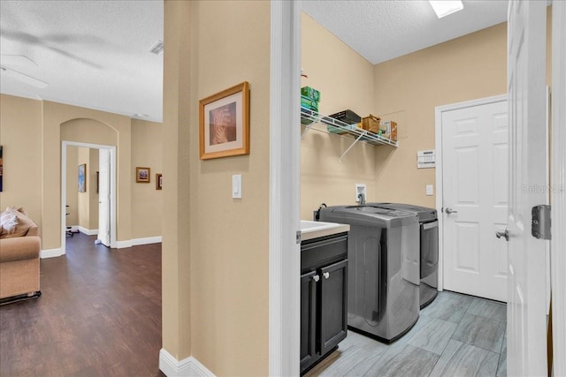 laundry area featuring cabinets, dark wood-type flooring, ceiling fan, a textured ceiling, and washing machine and clothes dryer