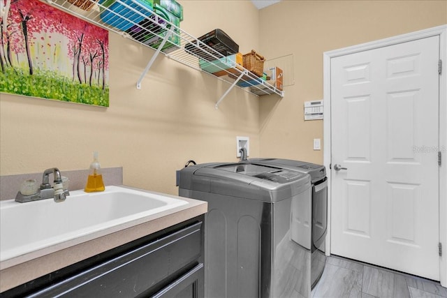 clothes washing area with washing machine and dryer and sink