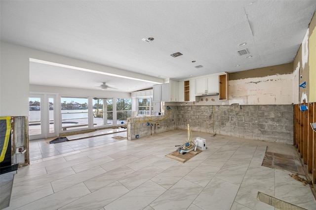 kitchen with ceiling fan, a water view, and white cabinetry