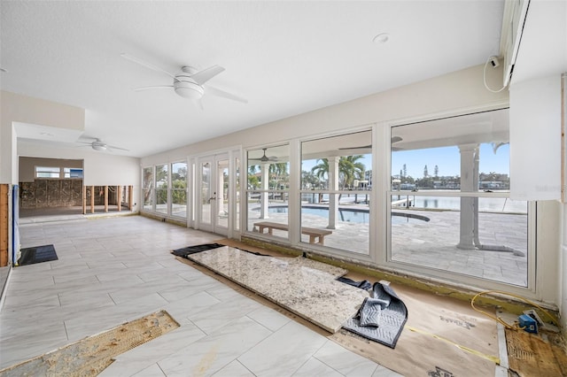 unfurnished sunroom with ceiling fan, french doors, and a water view