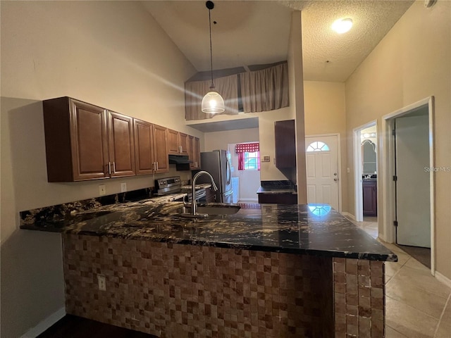 kitchen featuring high vaulted ceiling, decorative light fixtures, kitchen peninsula, and appliances with stainless steel finishes