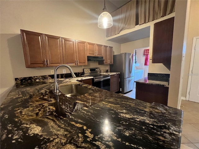 kitchen featuring sink, pendant lighting, dark stone counters, washer and clothes dryer, and appliances with stainless steel finishes