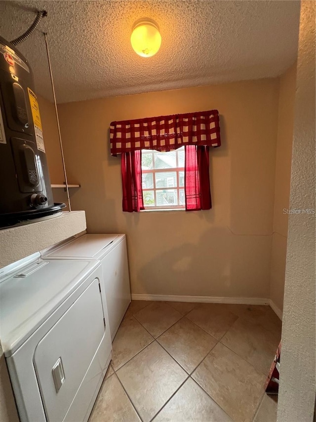 clothes washing area featuring water heater, light tile patterned flooring, washer and dryer, and a textured ceiling