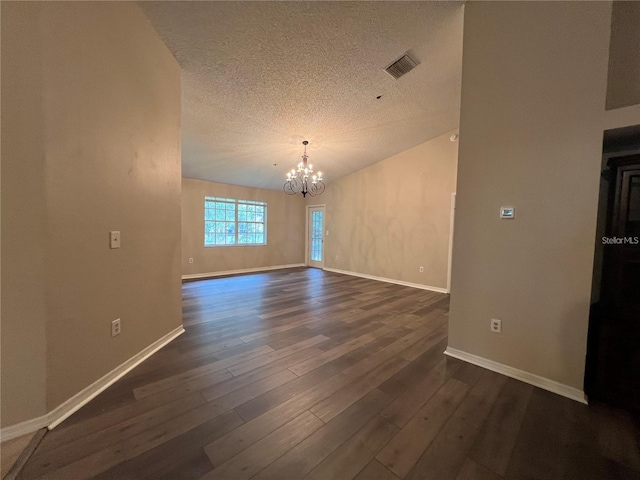 empty room featuring a textured ceiling, dark wood-type flooring, and an inviting chandelier