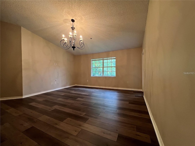 unfurnished room with a textured ceiling, dark hardwood / wood-style floors, and a notable chandelier