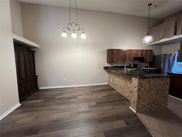 kitchen with hanging light fixtures, a high ceiling, dark hardwood / wood-style flooring, kitchen peninsula, and a chandelier