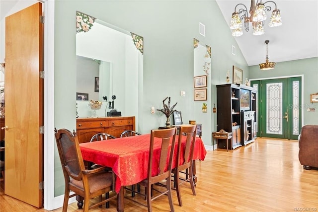 dining space featuring light hardwood / wood-style flooring, high vaulted ceiling, and a chandelier