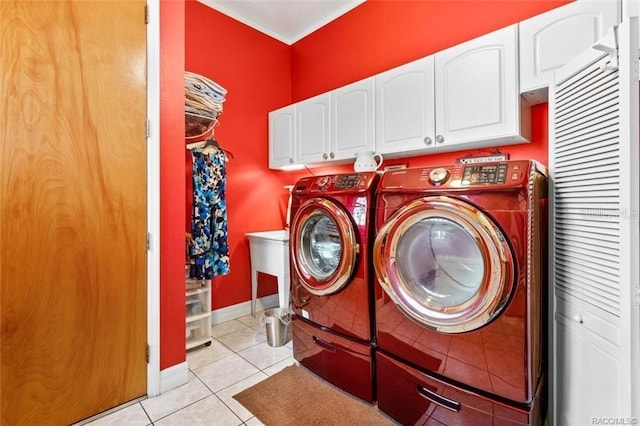 clothes washing area with washer and clothes dryer, cabinets, and light tile patterned floors