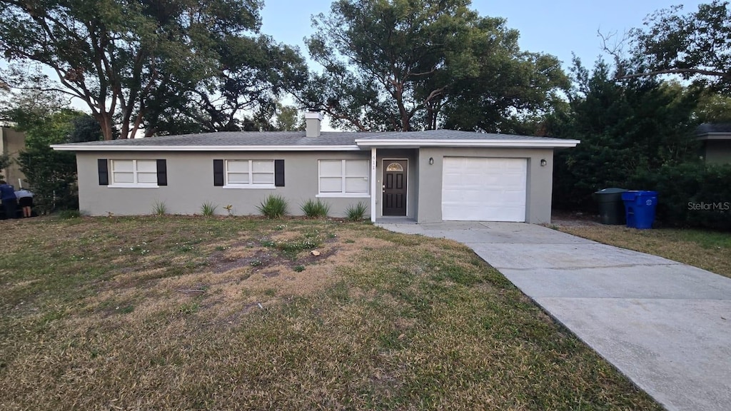 ranch-style home featuring a garage and a front lawn