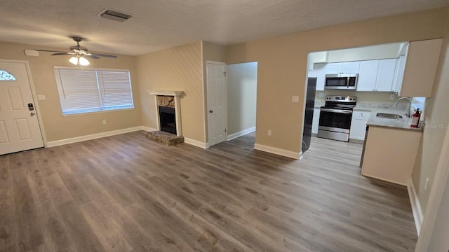 interior space with white cabinets, sink, ceiling fan, a fireplace, and stainless steel appliances