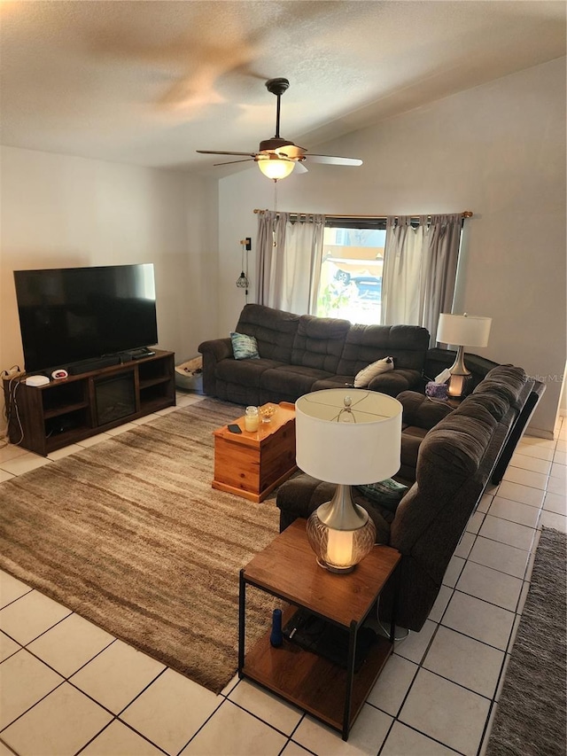 living room featuring ceiling fan, light tile patterned flooring, and vaulted ceiling