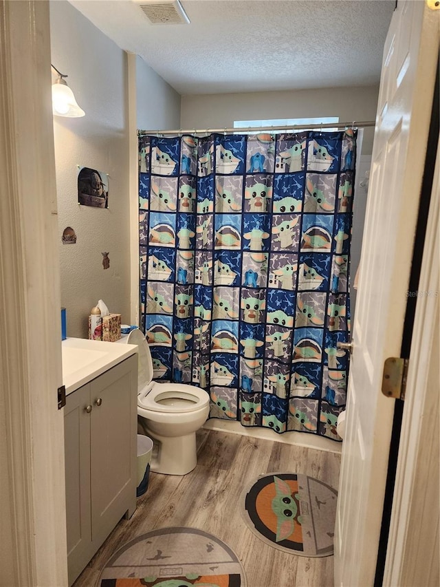 bathroom featuring vanity, toilet, wood-type flooring, and a textured ceiling