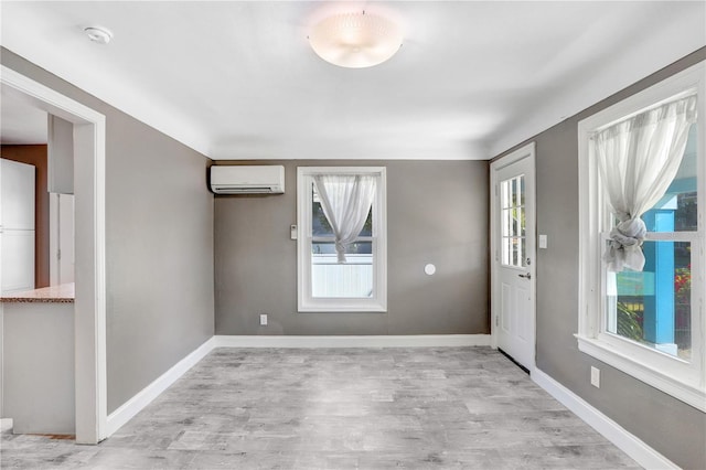 foyer entrance with a wall mounted air conditioner, light hardwood / wood-style floors, and plenty of natural light