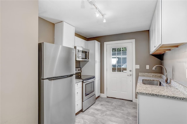 kitchen with light stone countertops, appliances with stainless steel finishes, white cabinetry, and sink