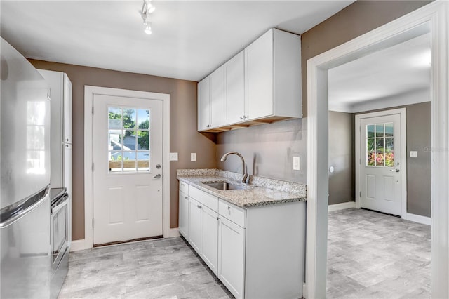 kitchen with white cabinets, a healthy amount of sunlight, sink, and fridge