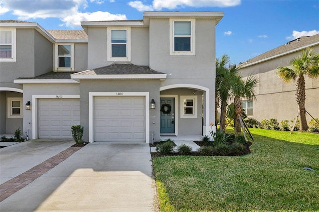 view of property with a front yard, roof with shingles, an attached garage, stucco siding, and concrete driveway