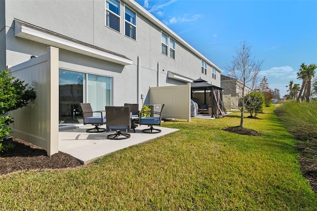 rear view of house with a patio area, stucco siding, a gazebo, and a yard