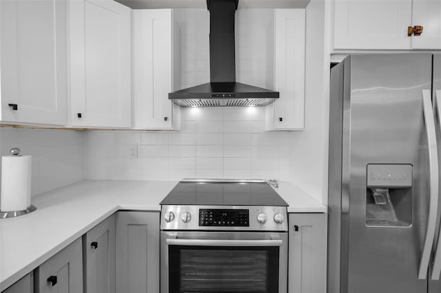 kitchen with appliances with stainless steel finishes, wall chimney exhaust hood, tasteful backsplash, and white cabinetry