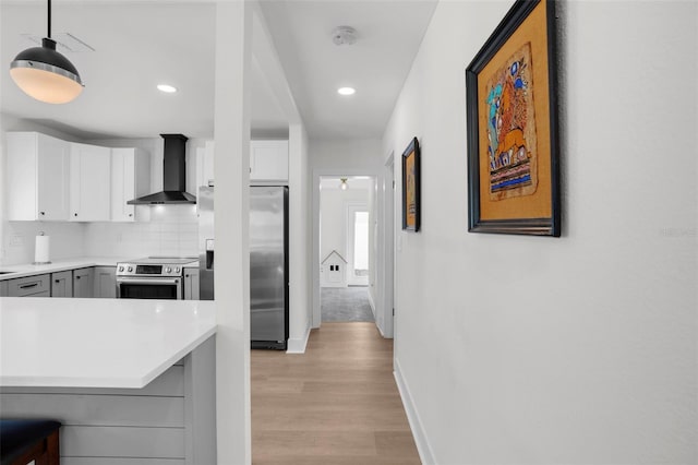 kitchen featuring gray cabinets, stainless steel appliances, decorative backsplash, wall chimney exhaust hood, and white cabinetry