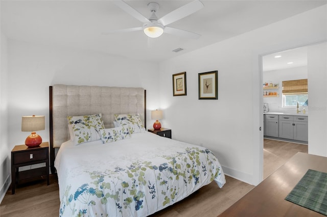 bedroom with ceiling fan, light hardwood / wood-style flooring, ensuite bathroom, and sink