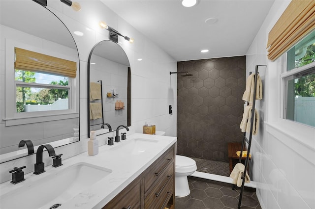 bathroom featuring a tile shower, tile patterned flooring, vanity, and a wealth of natural light