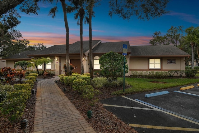 view of front of house with uncovered parking, a front lawn, and stucco siding