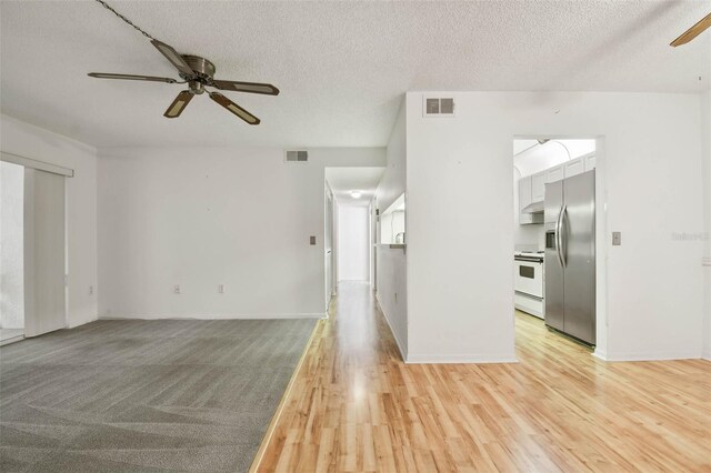 spare room with ceiling fan, a textured ceiling, and light hardwood / wood-style flooring