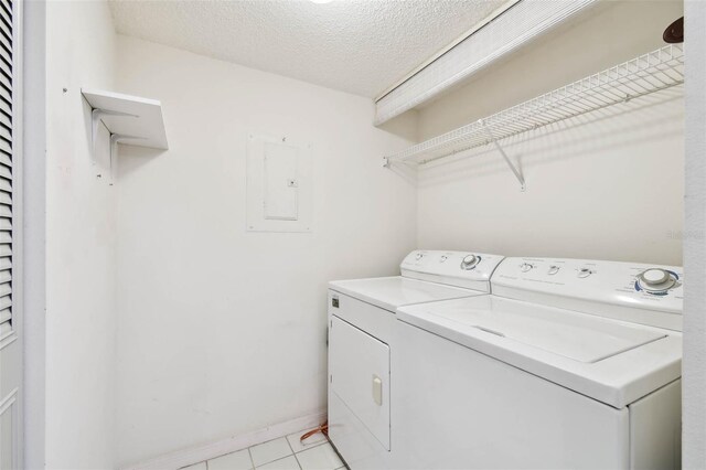 washroom featuring washer and dryer, light tile patterned floors, a textured ceiling, and electric panel