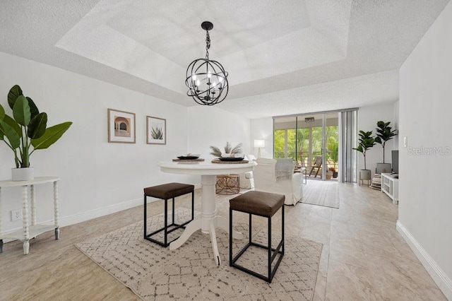 dining room with a tray ceiling, a wall of windows, and a notable chandelier