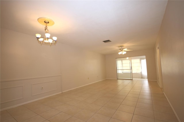 empty room with light tile patterned flooring and ceiling fan with notable chandelier