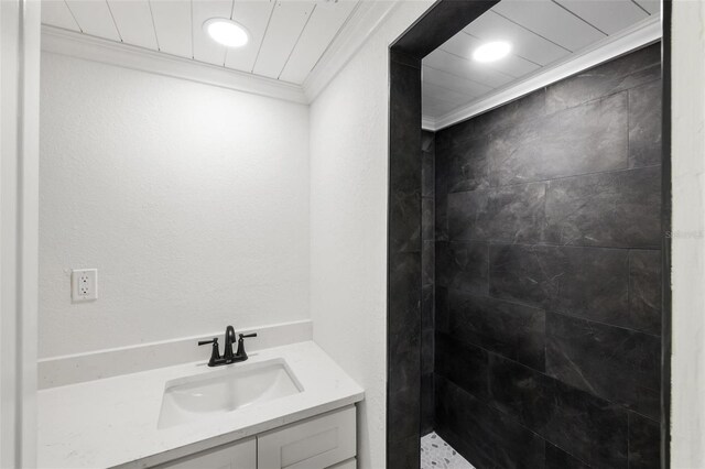 bathroom with tiled shower, vanity, and crown molding