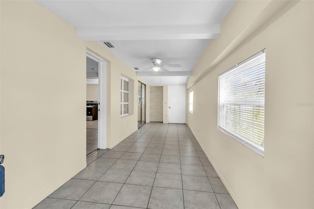 hallway featuring beamed ceiling and light tile patterned floors