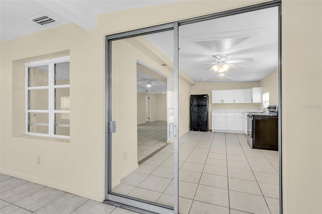 kitchen with white cabinets, black refrigerator, electric range, ceiling fan, and light tile patterned flooring