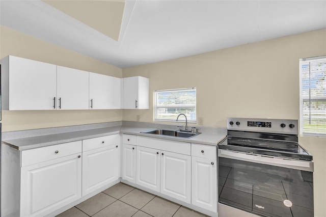 kitchen with a wealth of natural light, white cabinetry, sink, stainless steel range with electric stovetop, and light tile patterned floors