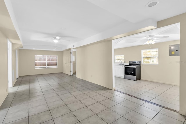 spare room with a wealth of natural light, ceiling fan, sink, light tile patterned floors, and electric panel