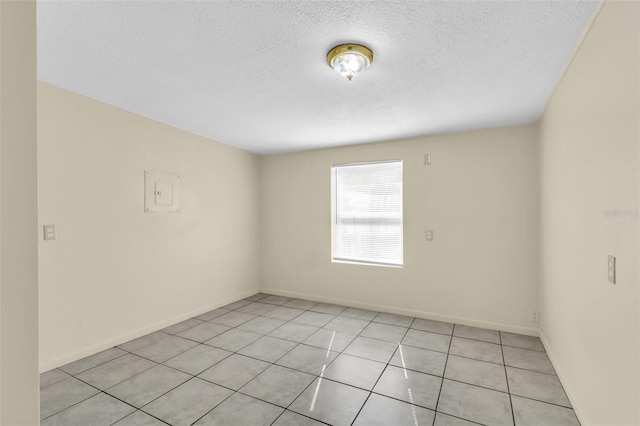 empty room with light tile patterned flooring and a textured ceiling