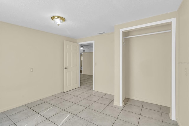 unfurnished bedroom with a closet, light tile patterned floors, and a textured ceiling